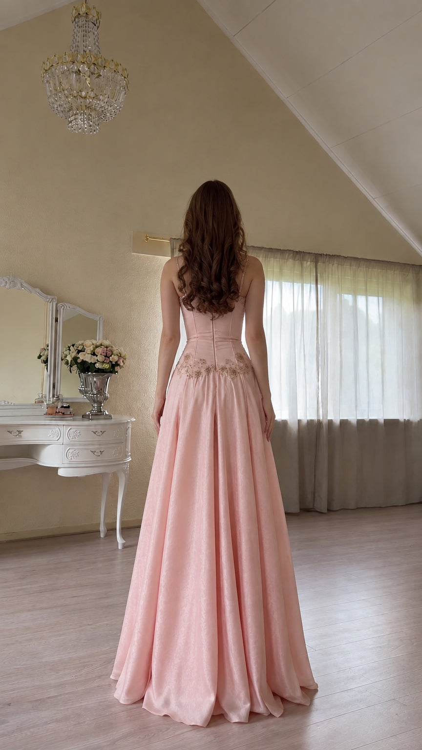 Back view of model wearing pink embroidered satin gown with lace-up corset closure
