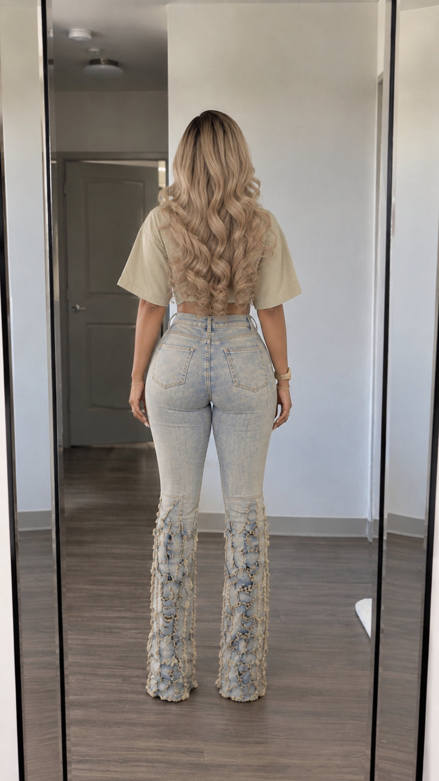 Back view of woman wearing beige crop top and high-waisted light-wash flare jeans with fringed bottom