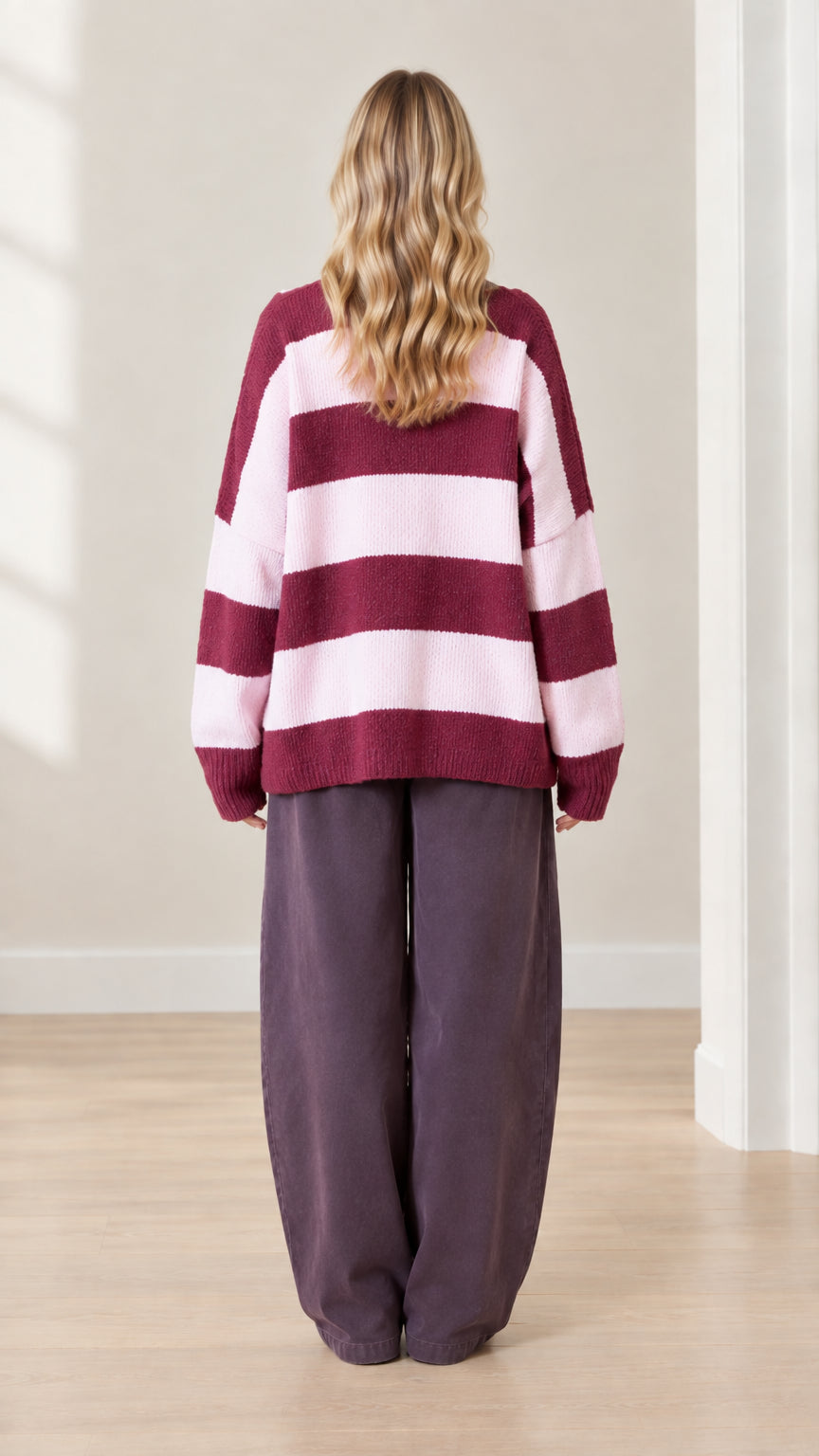 Back view of model showcasing wide maroon and pink horizontal stripes on knit cardigan