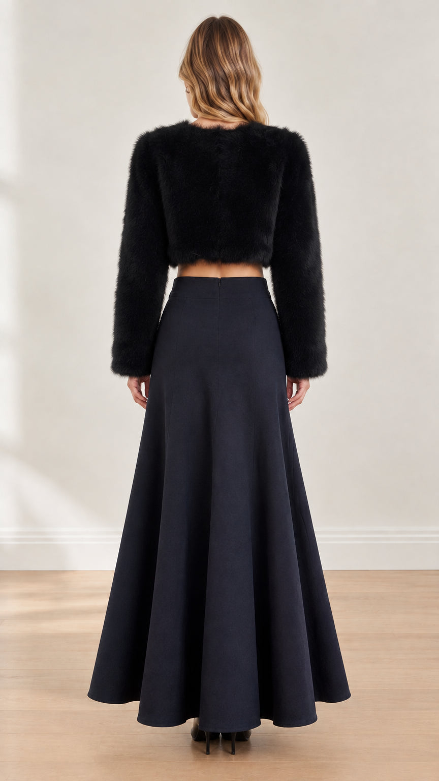 Back view of model in black fuzzy long sleeve cropped top and flared maxi skirt