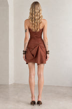 Back view of model wearing rust brown strapless draped mini dress