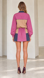 Back full view of woman wearing magenta colorblock long sleeve pullover and mini skirt