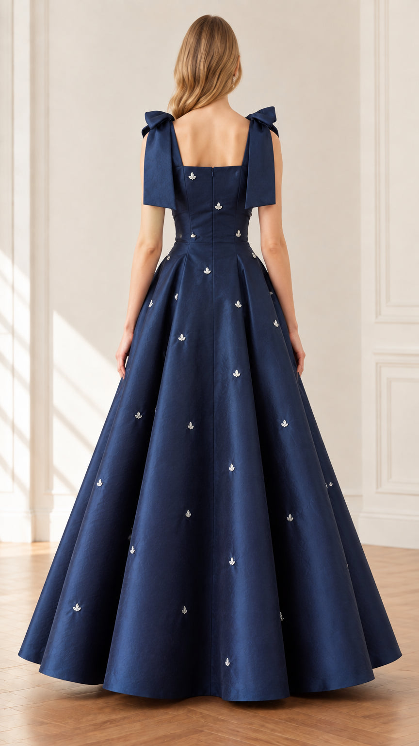 Back view of woman wearing navy blue pleated A-line ball gown with square back and bow straps