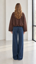 Back view of woman wearing brown jacket showing relaxed drop shoulder and gathered hem