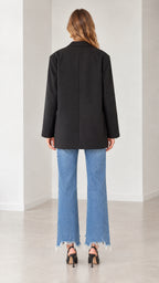 Back view of a model in an oversized black blazer paired with straight-leg denim