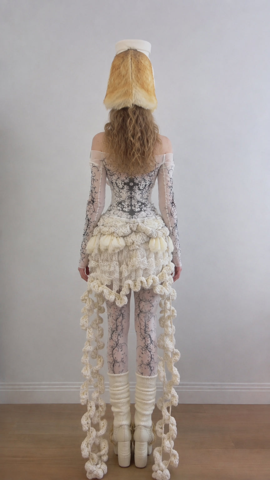 Back full-length view showing the cascading knit ruffle drape on the Cream bodysuit ensemble
