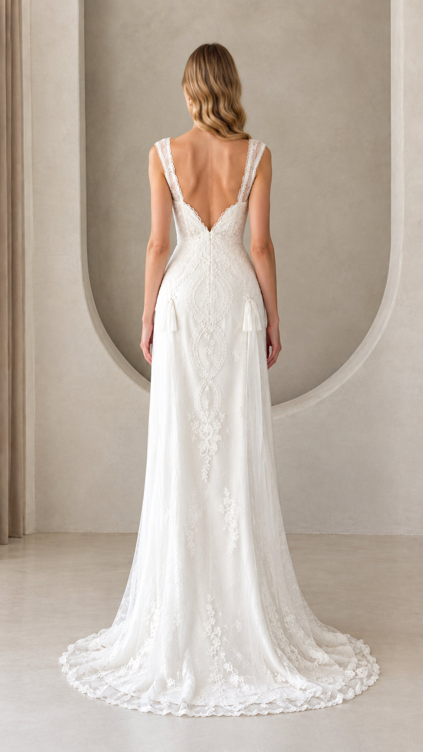 Back view of model wearing white lace evening dress showing deep V-back and sweep train