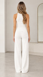 Back view of woman in white matching sleeveless top and wide leg trousers