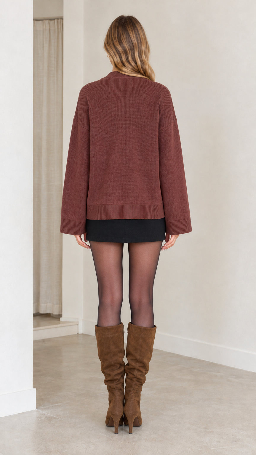 Back view of woman wearing brown knit cardigan showing loose relaxed fit and hip length