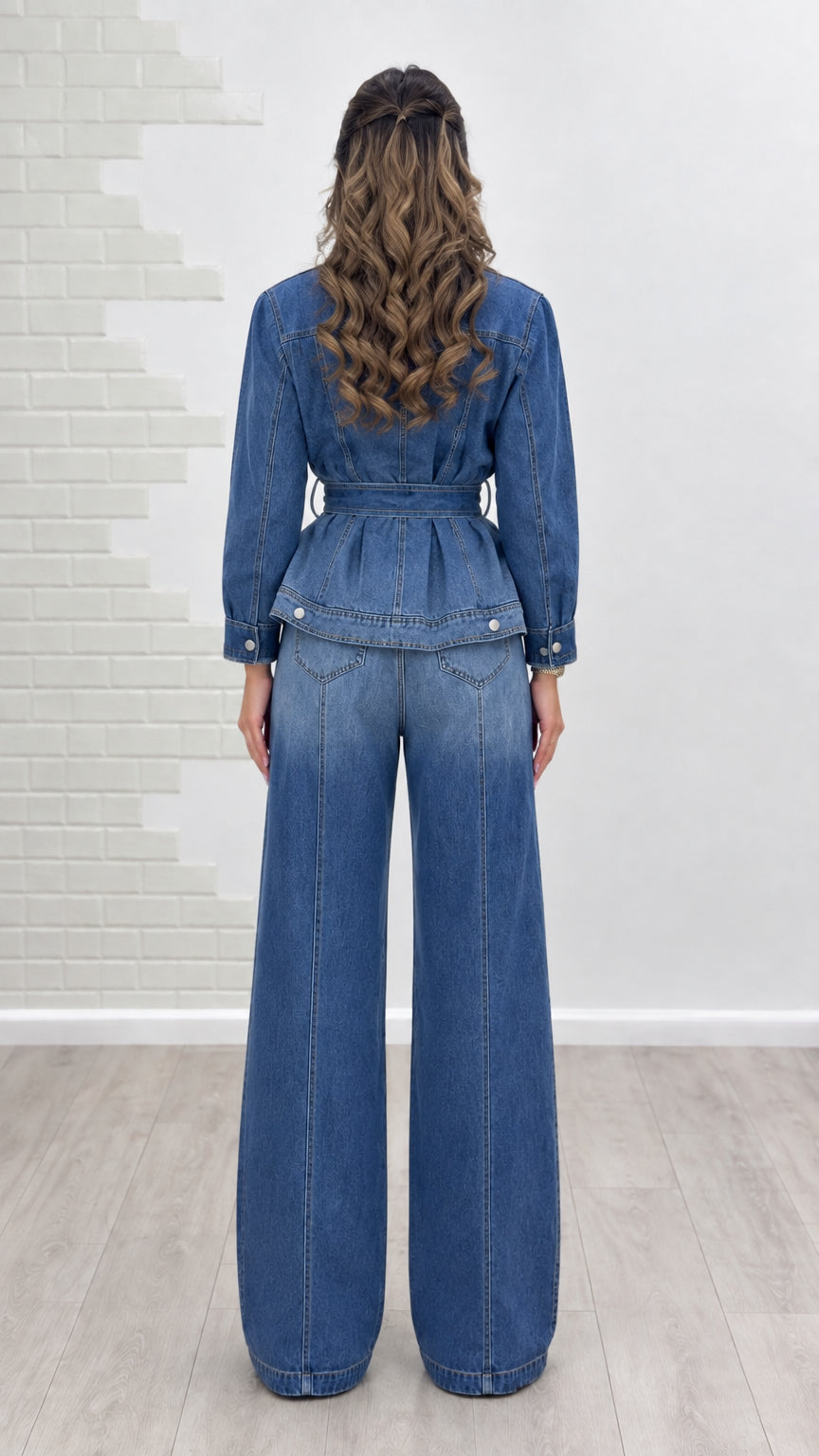 Back view of model showcasing belted peplum jacket and high-rise denim trousers
