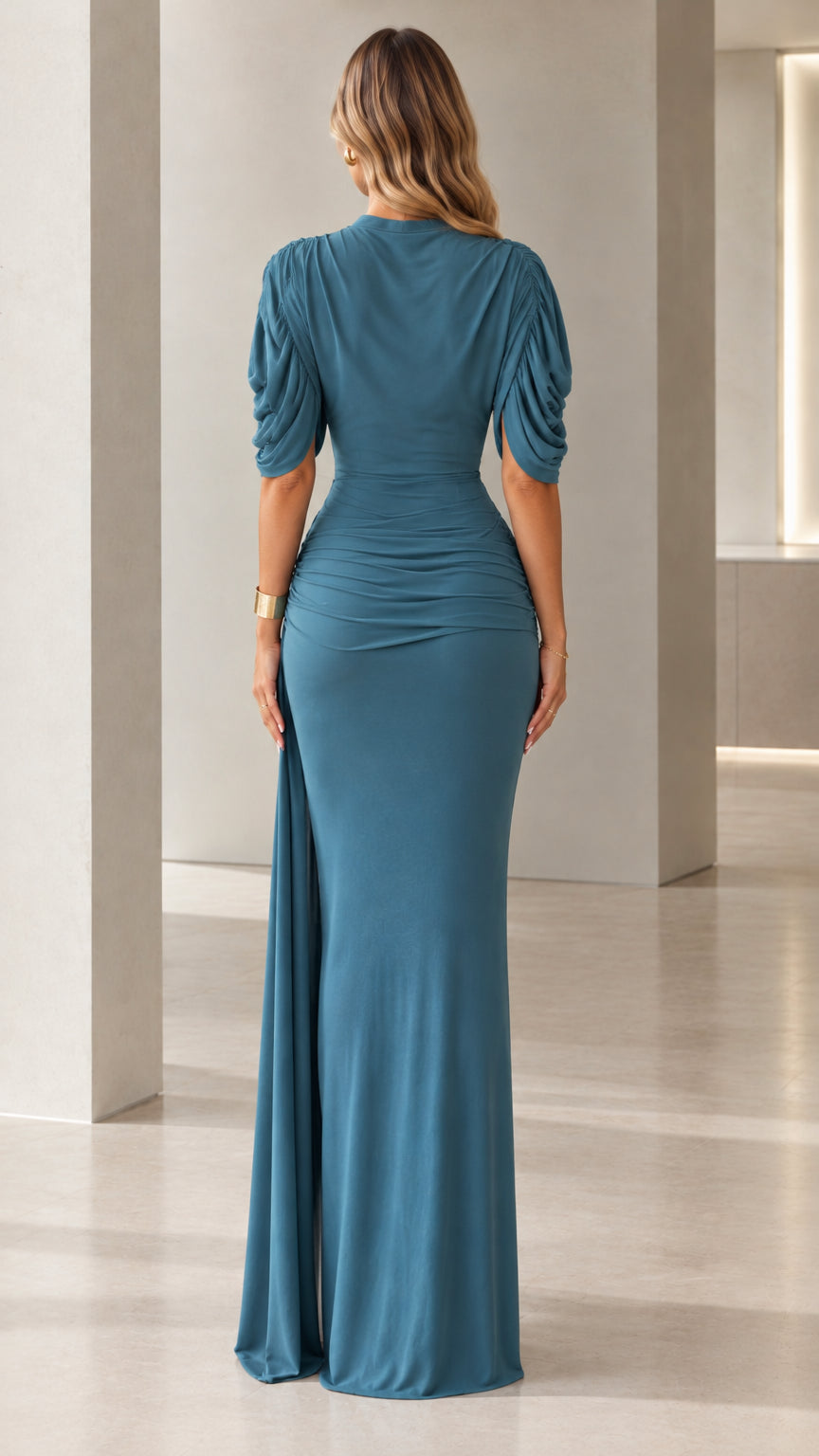Back view of woman wearing teal blue draped high neck maxi dress with ruched hips