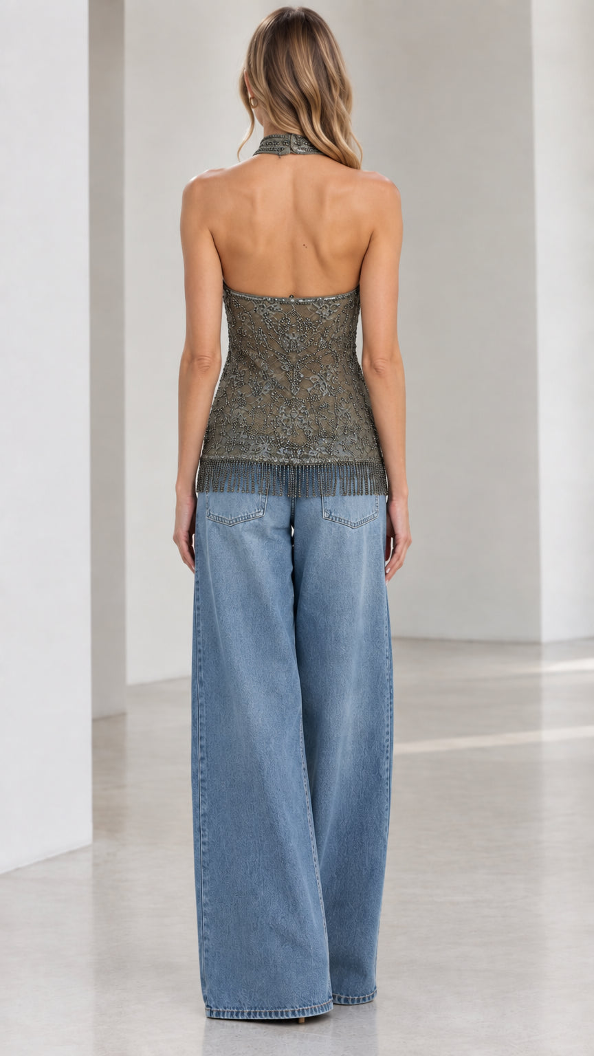 Back view of model wearing an open-back olive beaded halter top with fringe hem