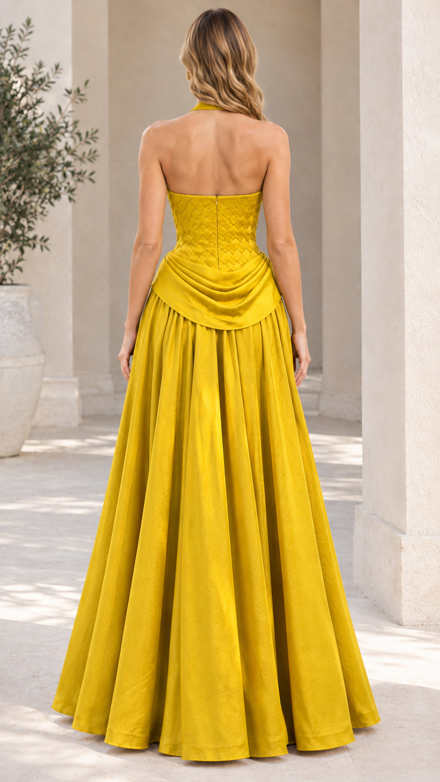 Back view of model showcasing the open back and full skirt of the yellow halter evening dress
