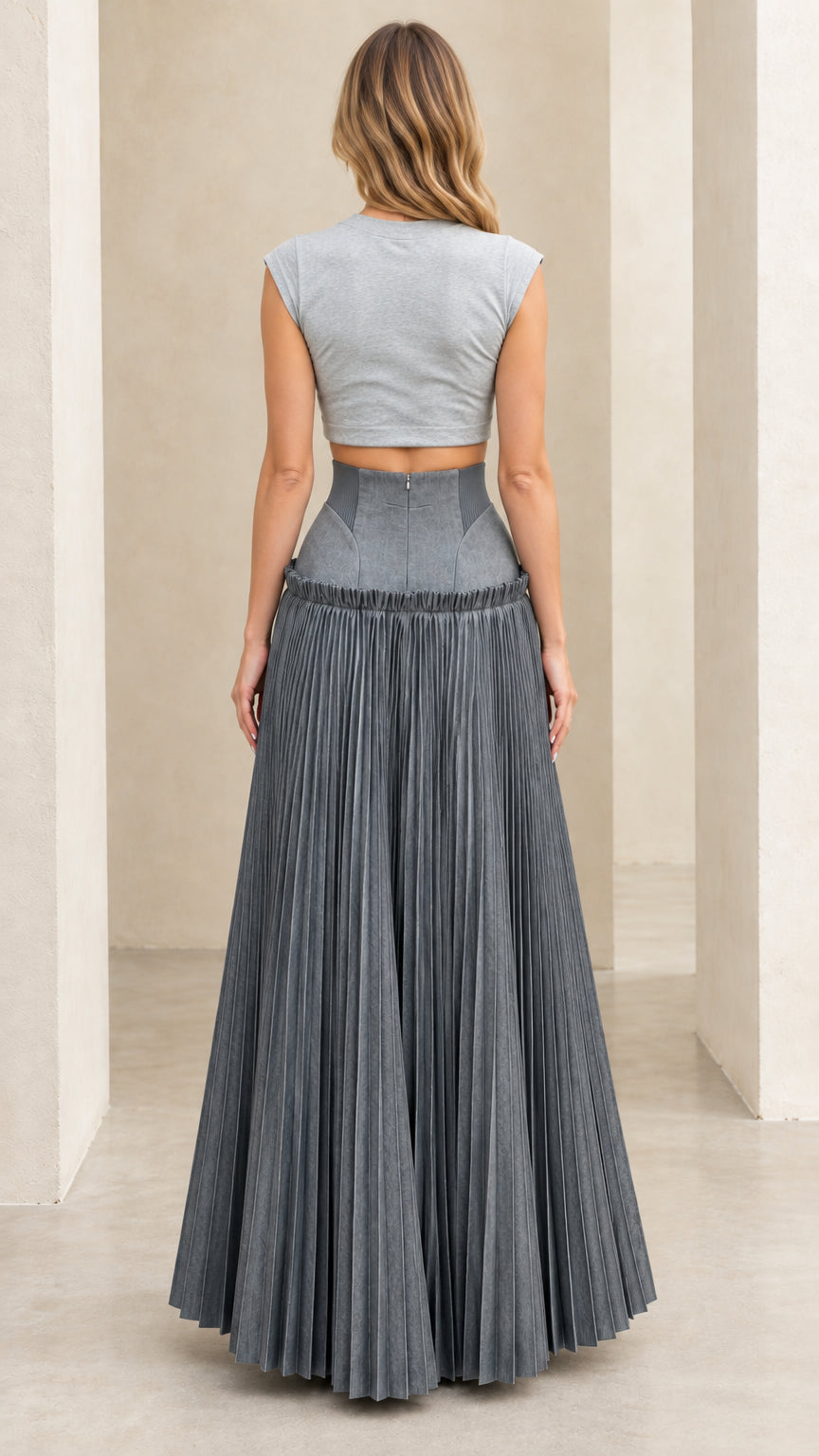 Back view of model wearing grey cropped top and high-rise pleated maxi skirt