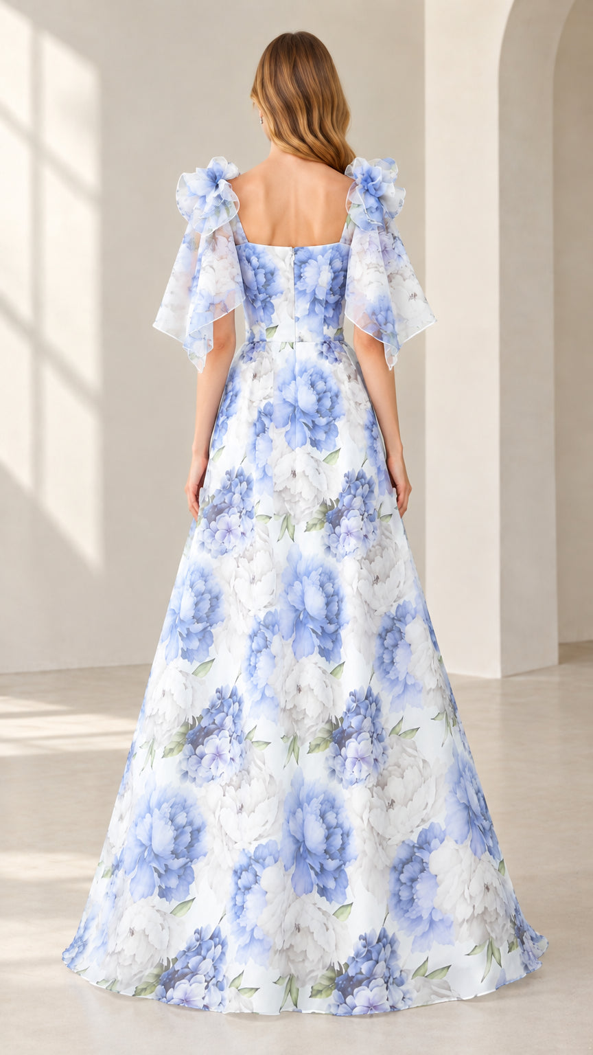 Back view of model showing square back and flowing skirt of white floral gown