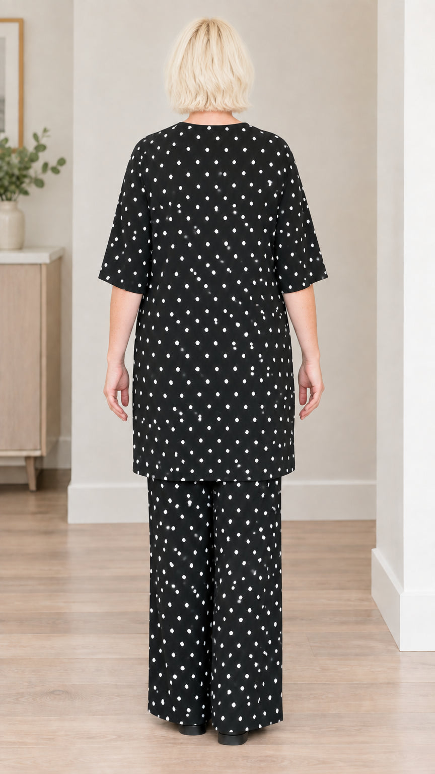Back view of woman wearing black polka dot tunic top and wide-leg pants