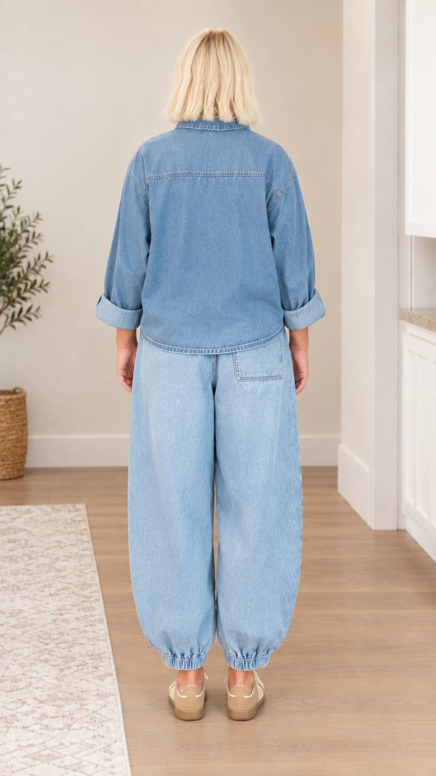 Back view of model wearing oversized light blue denim shirt and matching pants