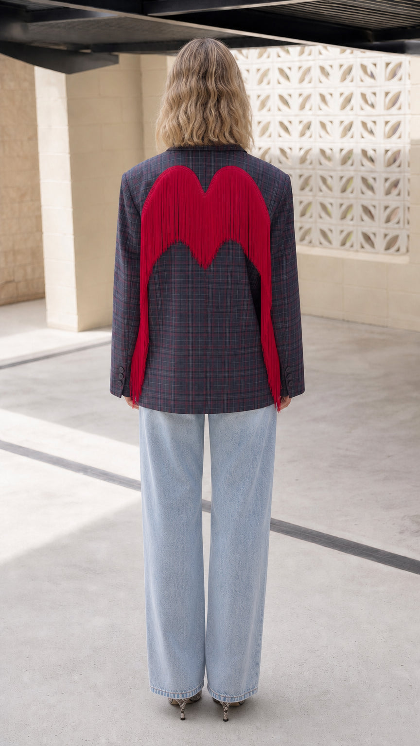 Back view of model showing red wing-shaped fringe across the Navy Plaid blazer