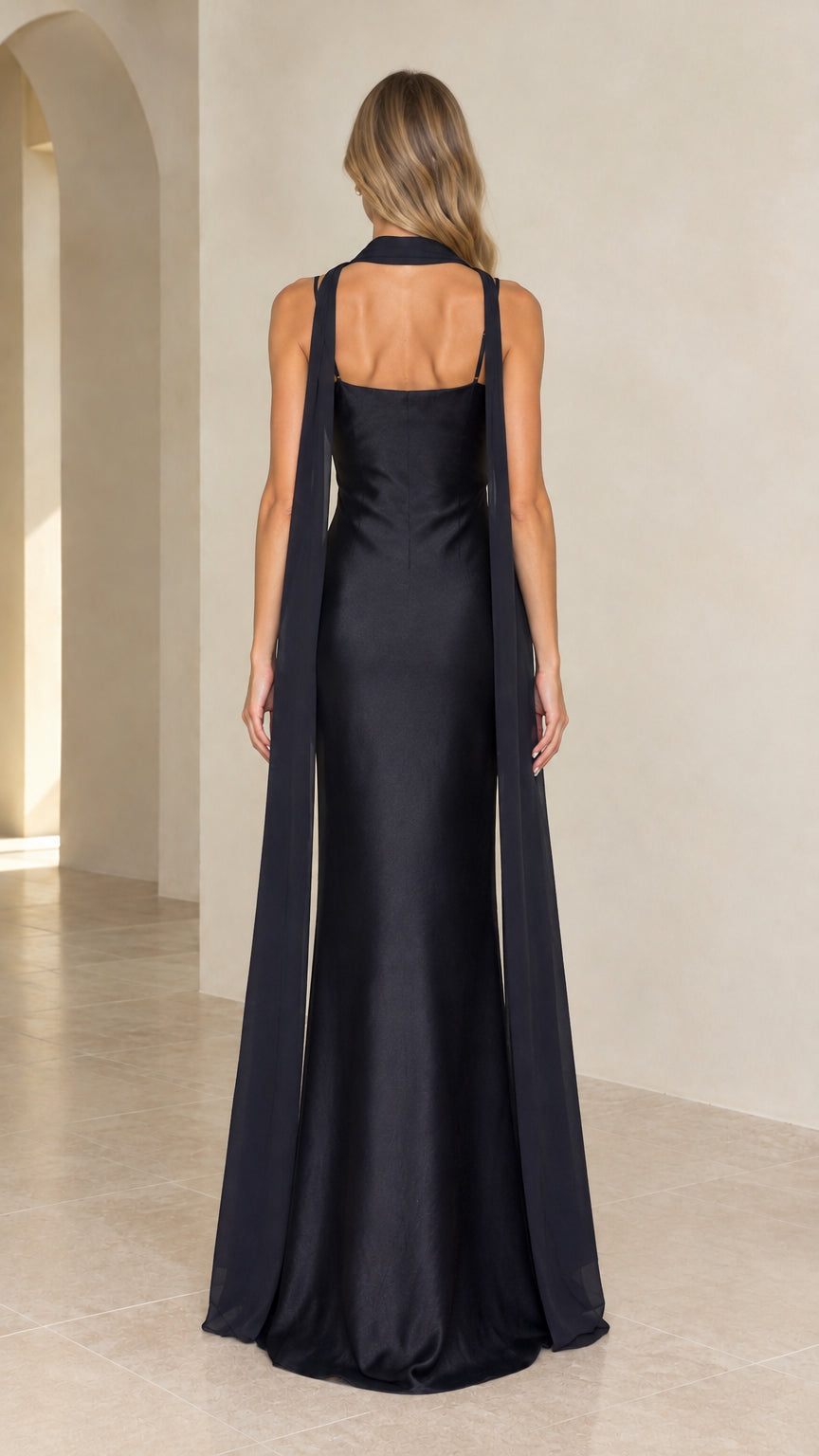 Back view of black satin evening gown highlighting the trailing capelet streamers