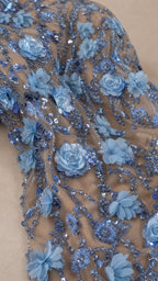 Close-up detail of blue 3D flower appliques and shimmering sequin embroidery on mesh