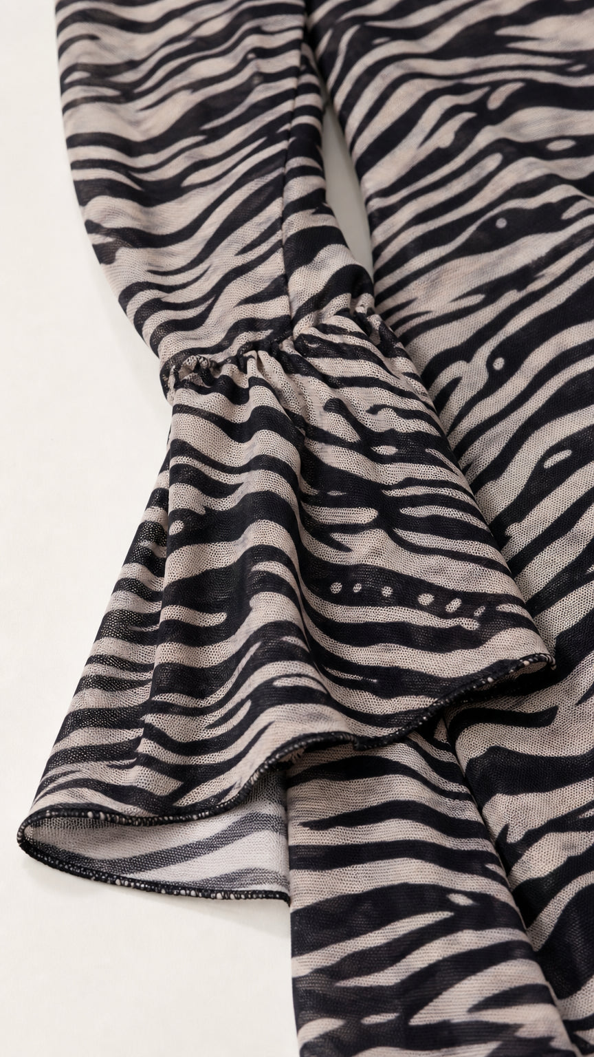 Close-up detail of sheer zebra print mesh sleeve with gathered flared bell cuff
