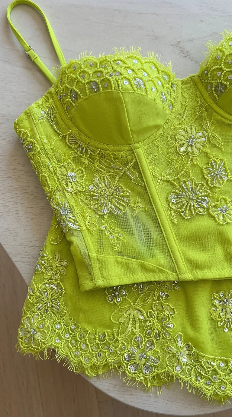 Close-up flat lay of lime green floral lace corset top and scalloped mini skirt hem
