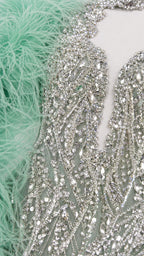 Close-up detail of intricate crystal beadwork, sequins, and mint green feather trim