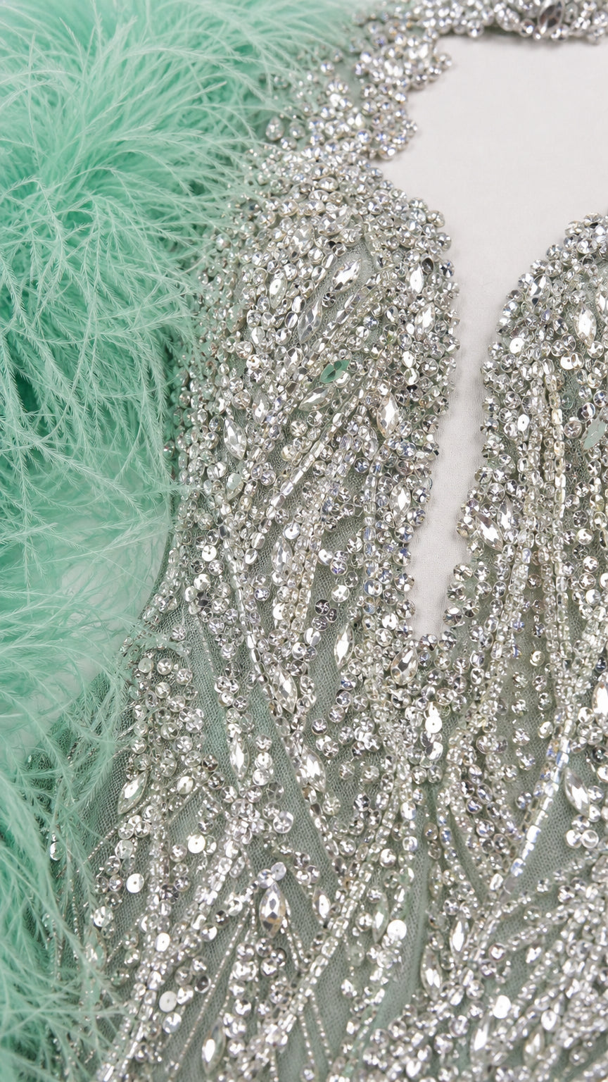 Close-up detail of intricate crystal beadwork, sequins, and mint green feather trim