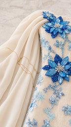 Detailed close-up of 3D blue sequined floral appliques and chiffon fabric on the ivory gown