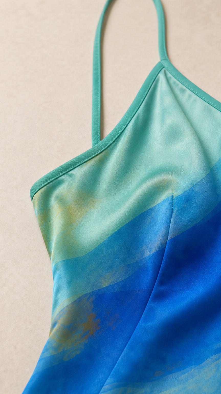 Close-up detail of satin fabric neckline and strap on aqua print dress