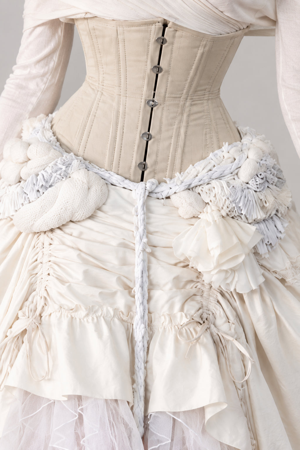 Close-up detail of structured corset waist with hook closures and ruffled fabric trim