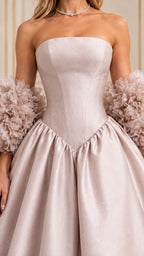 Close-up detail of structured strapless bodice, basque drop waistline, and ruffled arm cuffs