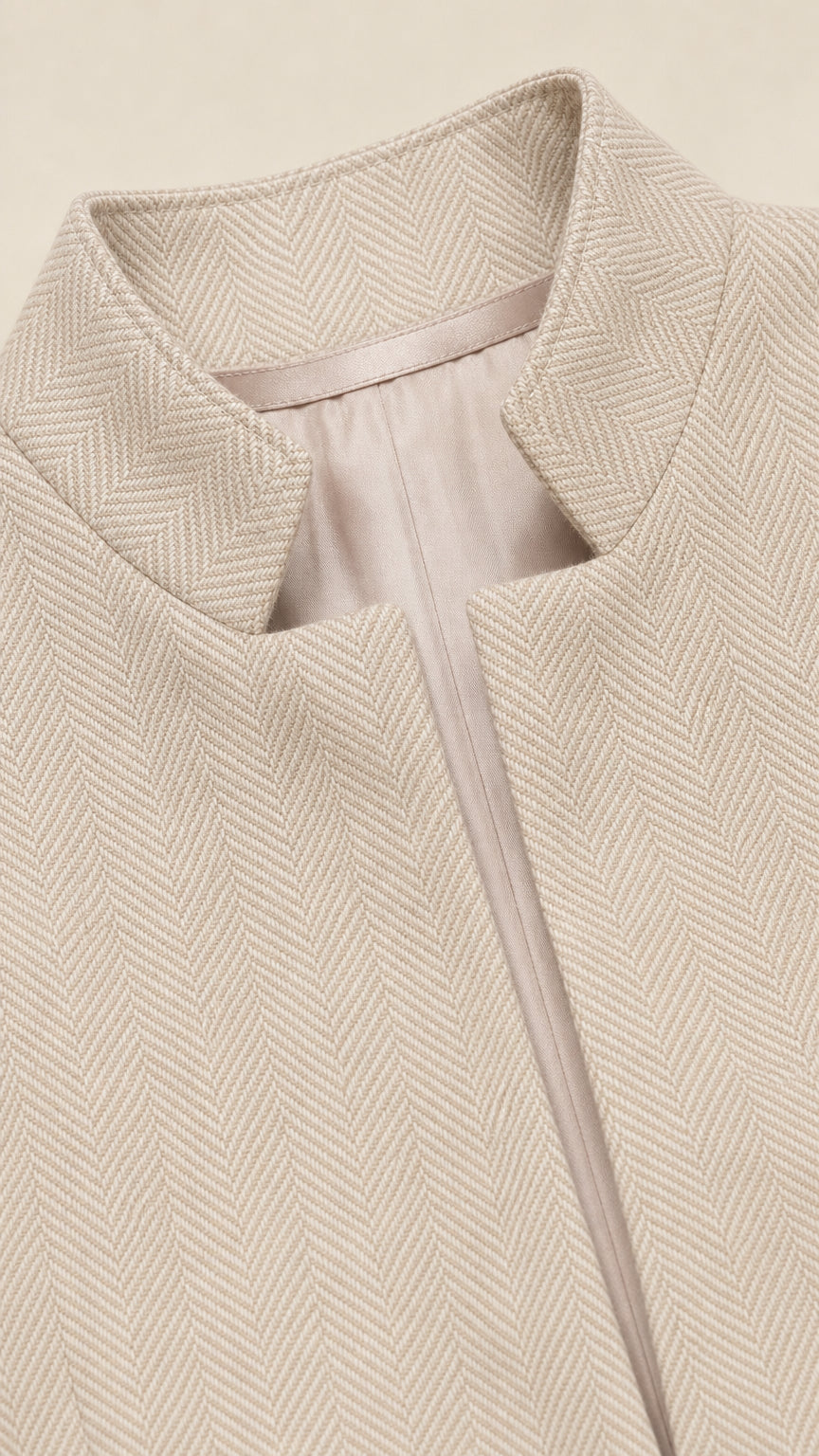 Close-up detail of beige blazer stand collar and textured herringbone weave