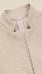 Close-up detail of beige blazer stand collar and textured herringbone weave