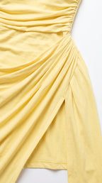 Close-up detail of gathered fabric ruching and side slit on yellow maxi dress