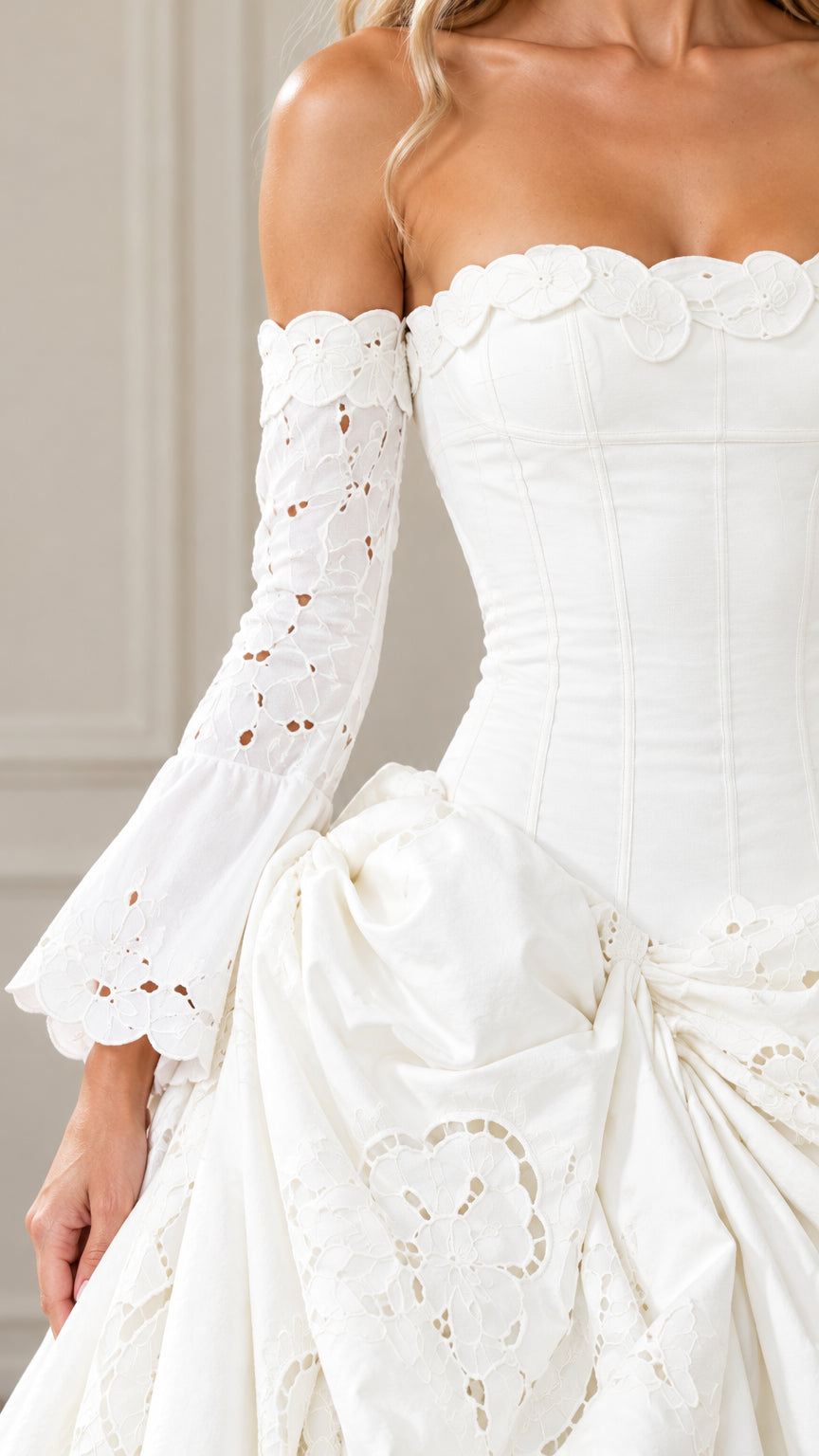Close-up detail of white corset bodice, scalloped neckline, flared sleeve, and cutwork embroidery