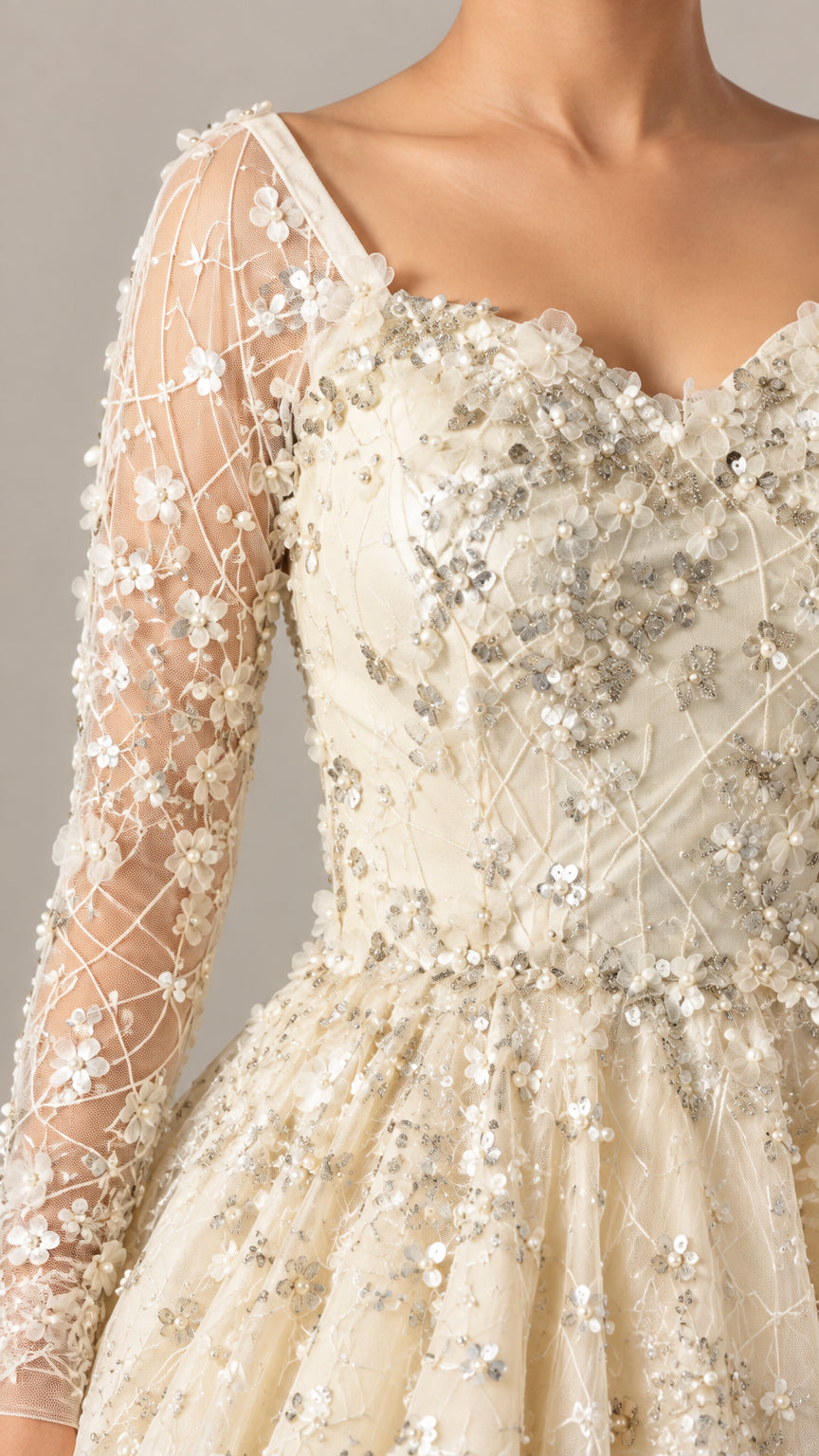 Close up view of champagne sequin floral embroidery and sheer long sleeve