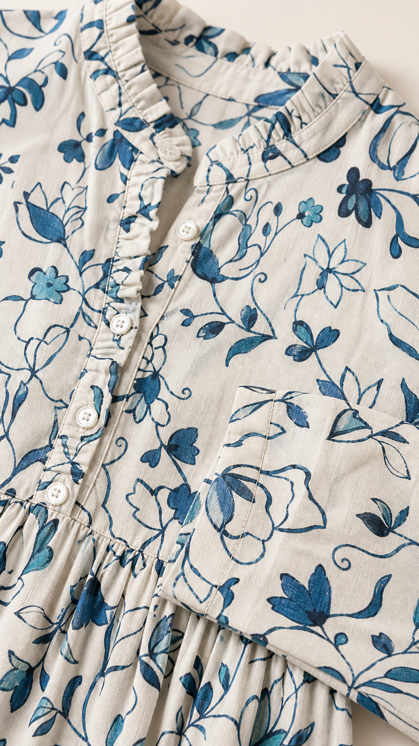 Close-up detail of ruffled collar, button placket, and floral print fabric texture