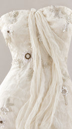 Close-up detail of bodice showing gathered draped fabric and floral bead embroidery