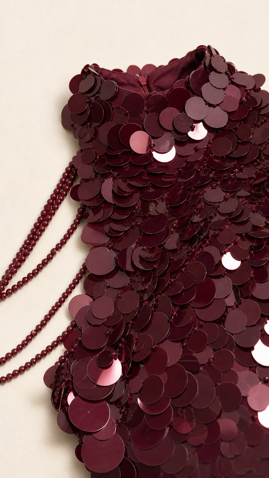 Close-up detail of burgundy paillette sequins and delicate beaded shoulder strands