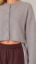 Close-up detail of cropped knit cardigan texture, button placket, and striped pant waistband