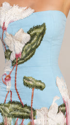 Detailed close-up of intricate botanical embroidery and fringed hemline on light blue gown