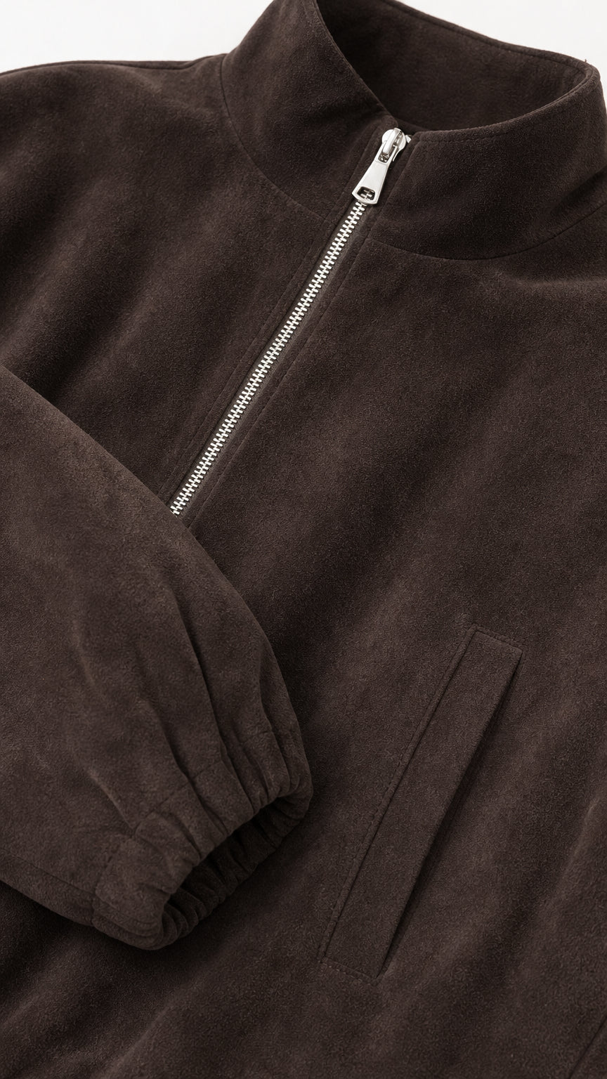 Close-up detail of dark brown fleece texture, metal zipper, and elastic cuff