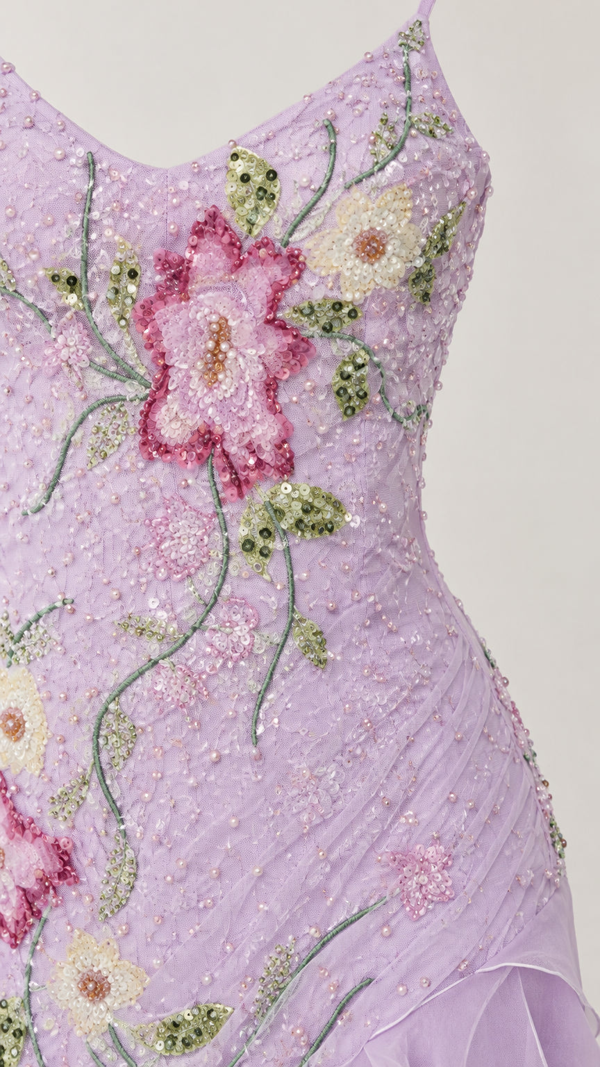 Close-up detail of lilac fabric with intricate pink floral embroidery, beadwork, and sparkling sequin accents