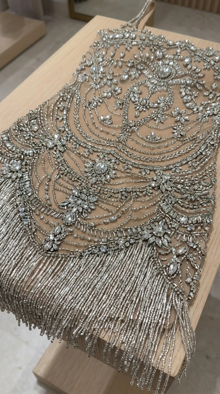 Close-up flat lay of intricate silver rhinestone and beadwork detailing with fringe hem