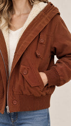 Close-up detail of brown jacket showcasing plush fleece hood lining and button pocket flap