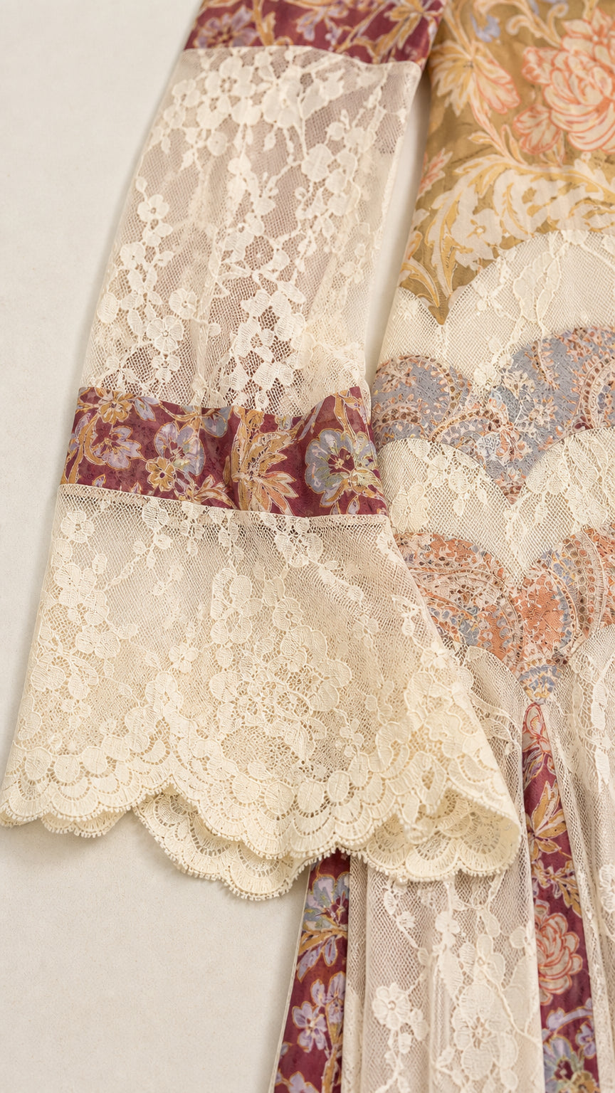Close-up detail of scalloped lace cuffs and printed tapestry accents on maxi dress sleeve