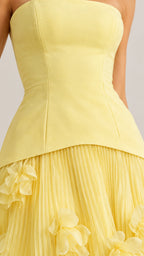 Close-up detail of structured bodice and pleated skirt seam with 3D floral accent