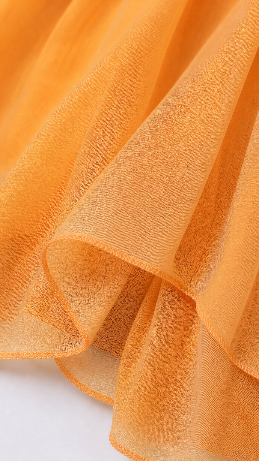 Close-up detail of lightweight sheer orange chiffon fabric and hem finish
