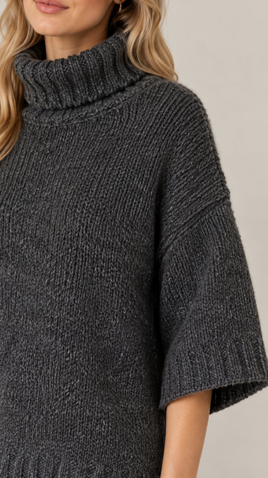 Close-up detail of textured knit fabric and folded ribbed turtleneck collar in dark grey